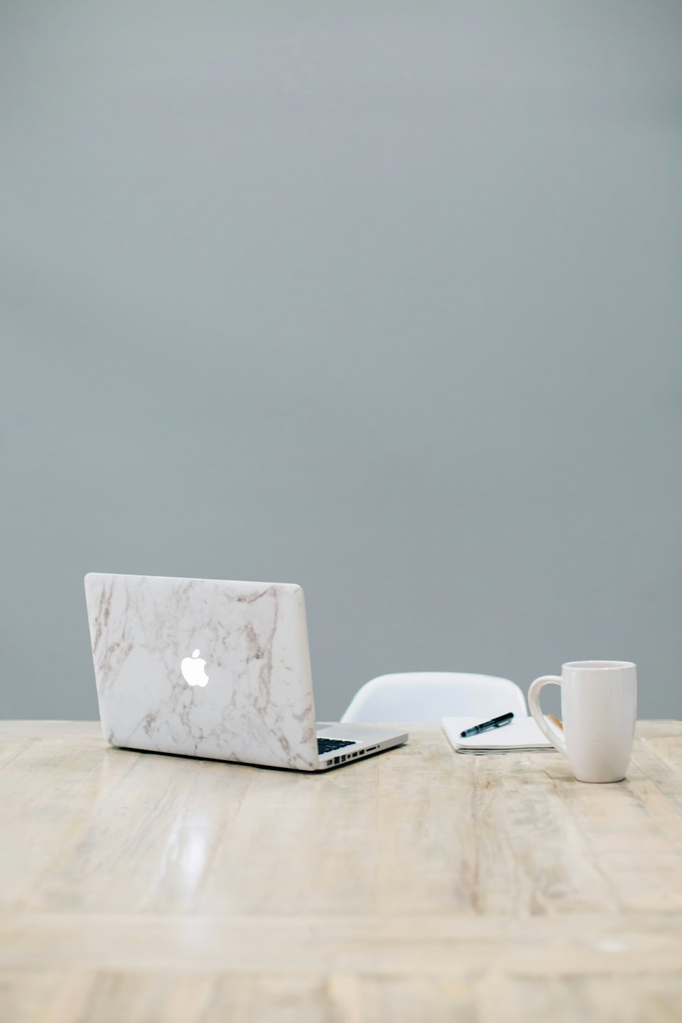 Portátil, cuaderno y taza de café sobre un escritorio de madera.